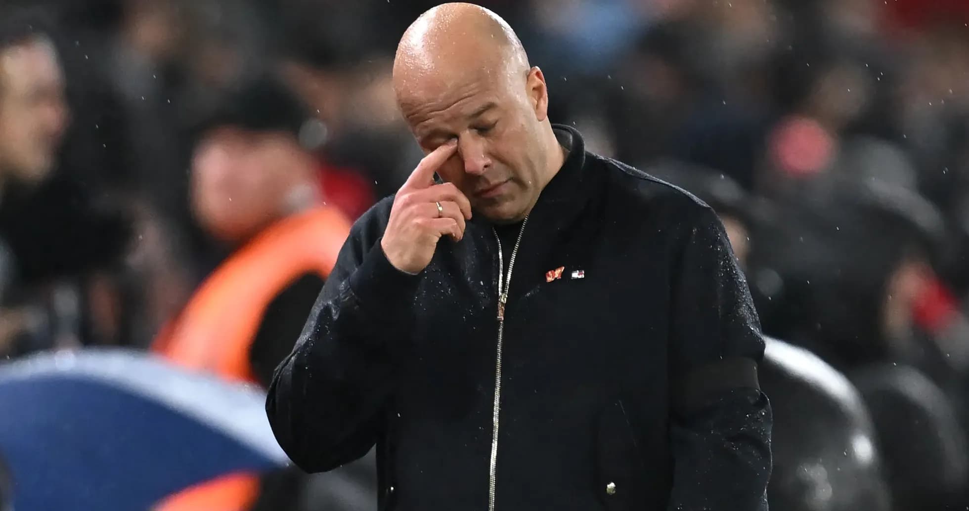 Coach wiping his eye during rainy match