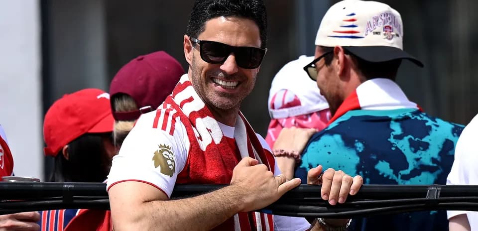 Man smiling and wearing an Arsenal scarf at event