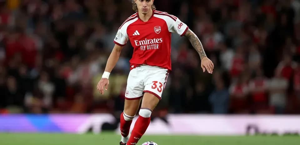 Player in Arsenal kit running with the ball