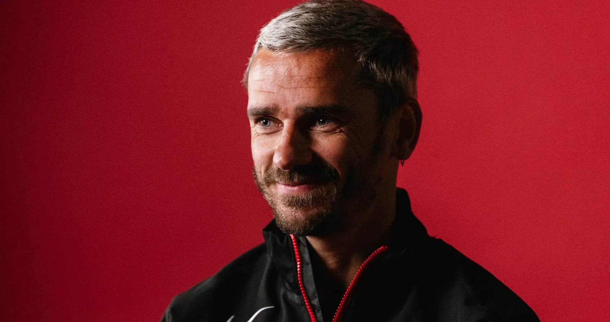 Man smiling in a black jacket against red background