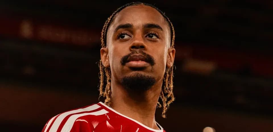 Player wearing red jersey posing at stadium