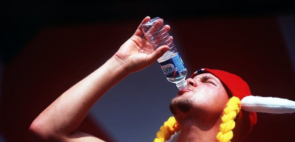 Person in hat drinking water from bottle