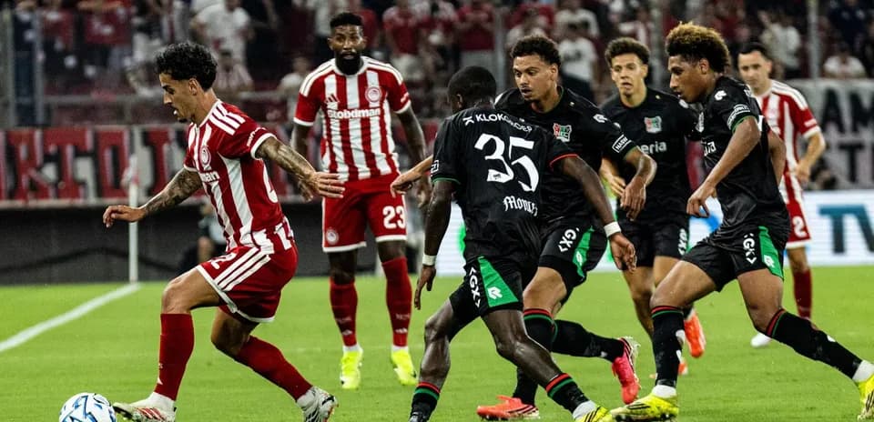 Olympiakos player dribbling against NEC defenders