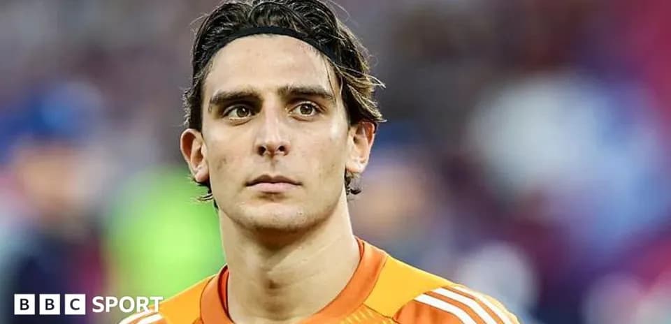 Goalkeeper in orange kit looking intently