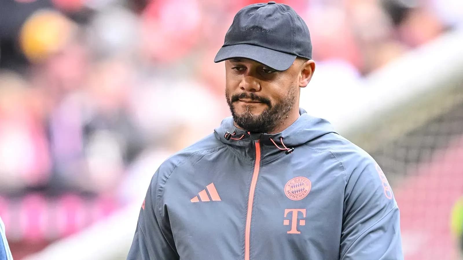 Person wearing Bayern Munich jacket and cap on field