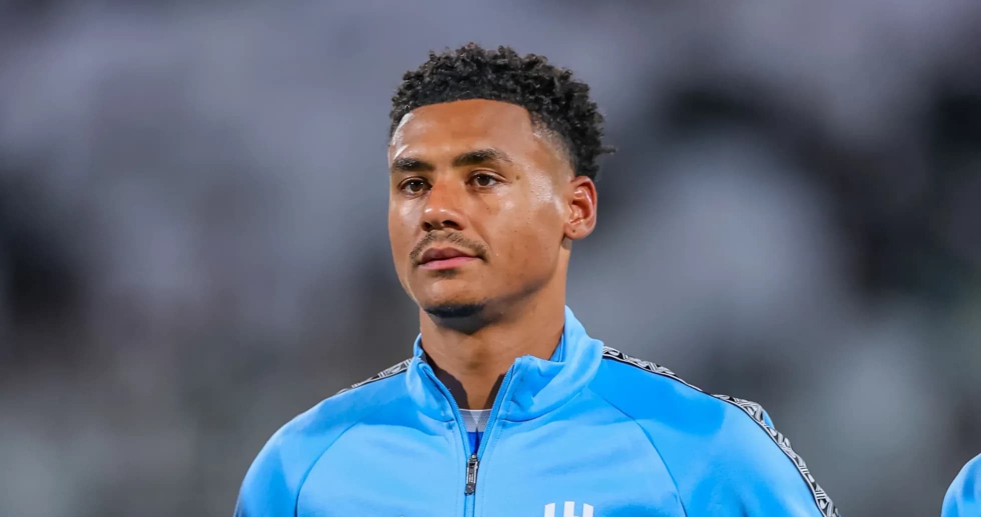 Player in blue training jacket on field