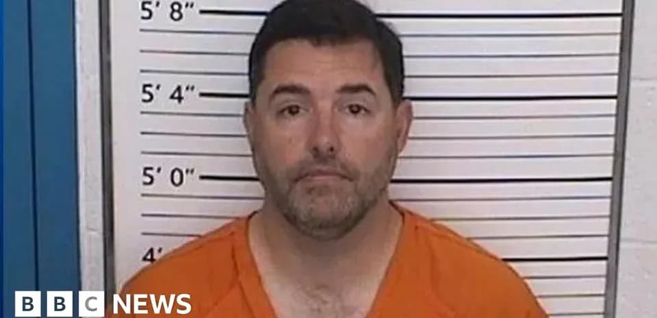 Man in orange jumpsuit at police mugshot wall