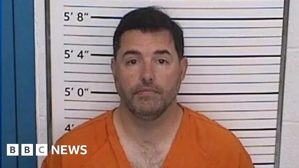 Man in orange jumpsuit at police mugshot wall