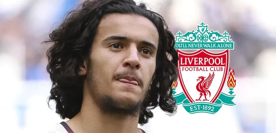 Player with curly hair near Liverpool FC logo
