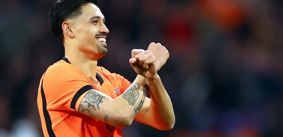 Player celebrating in orange jersey with tattoos