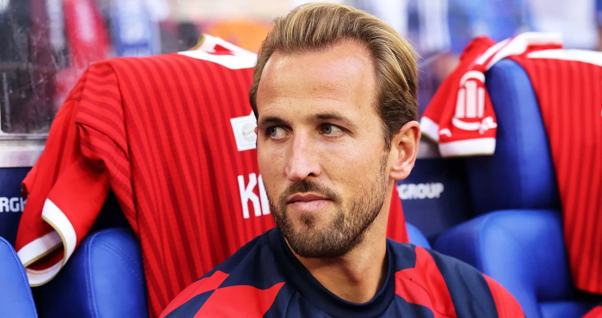 Player sitting on bench with red jersey behind
