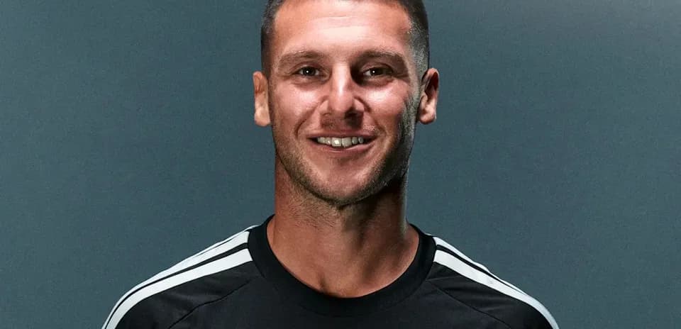 Player posing in team jersey against gray background