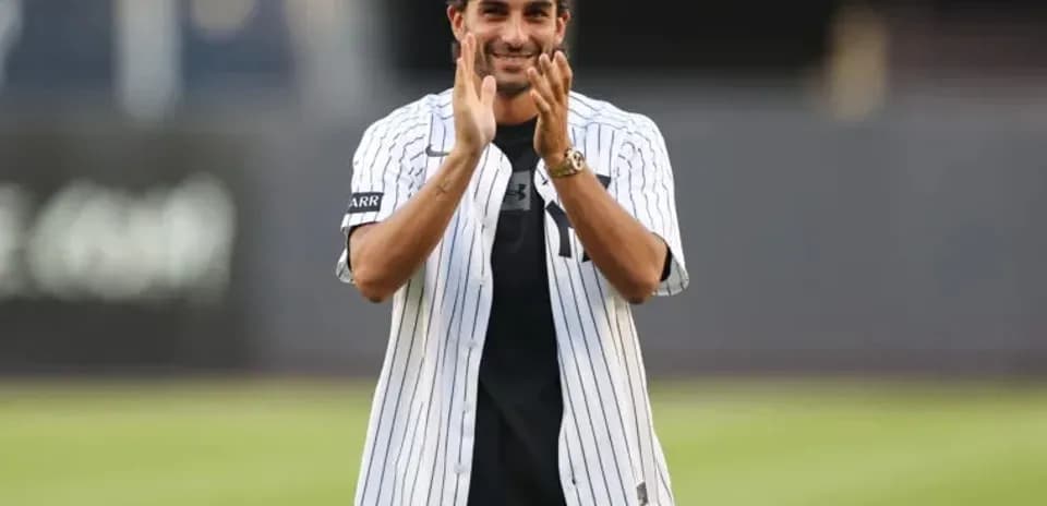 Man in Yankees jersey clapping at baseball field