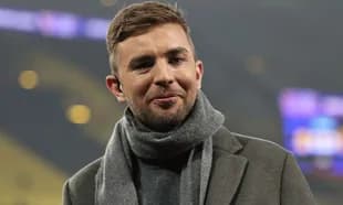 Man in a coat and scarf smiling at camera