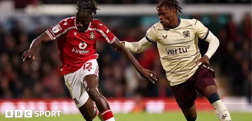 Player in red jersey dribbling past opponent in beige