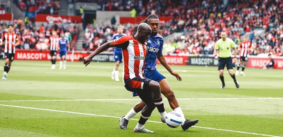 Brentford player challenging Fulham opponent for the ball