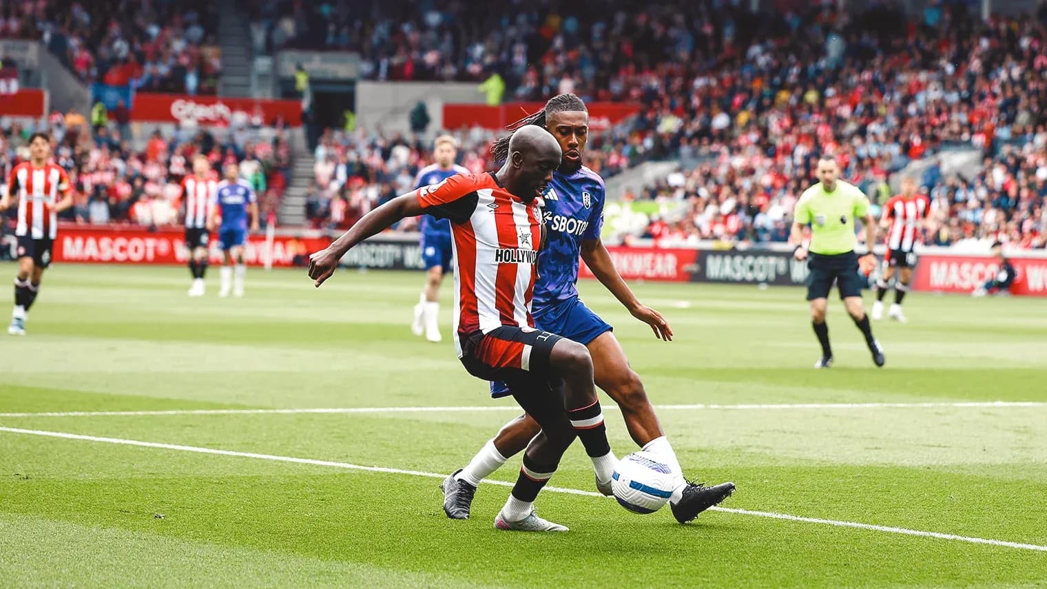 Brentford player challenging Fulham opponent for the ball