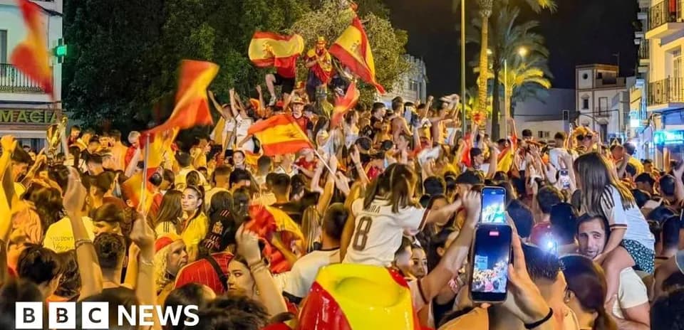 Crowd celebrating with flags in nighttime street