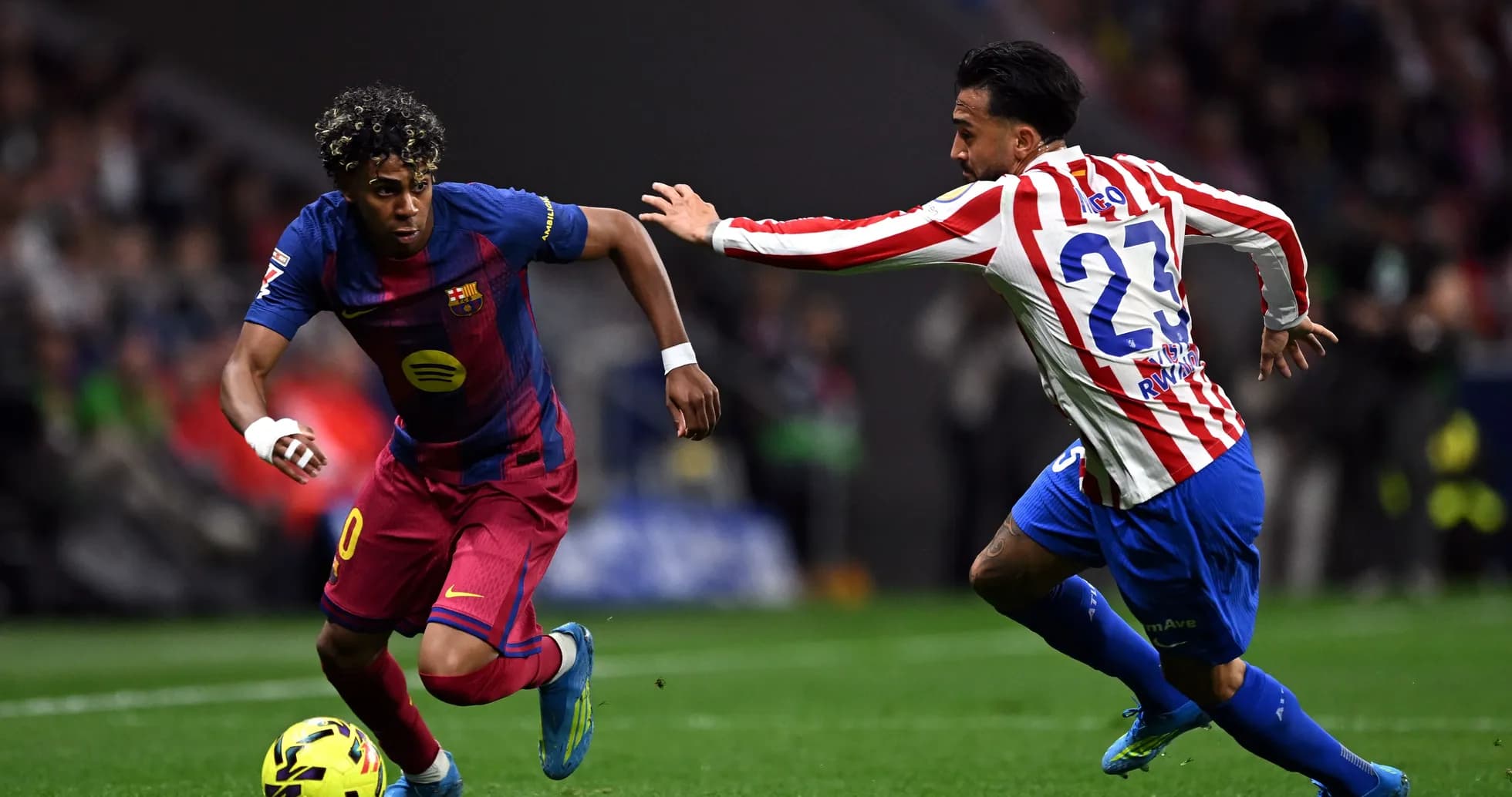 Barcelona player dribbling past Atlético defender during match