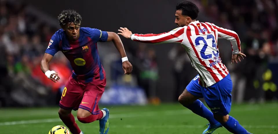 Barcelona player dribbling past Atlético defender during match