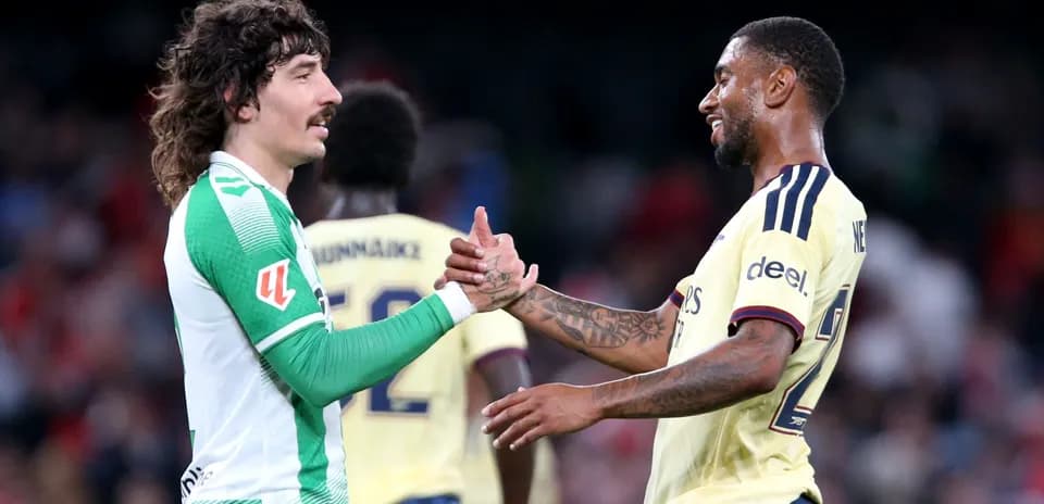 Two football players shaking hands on the pitch