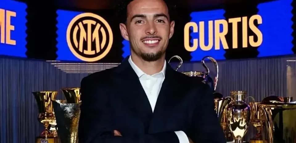Man posing with trophies at event backdrop