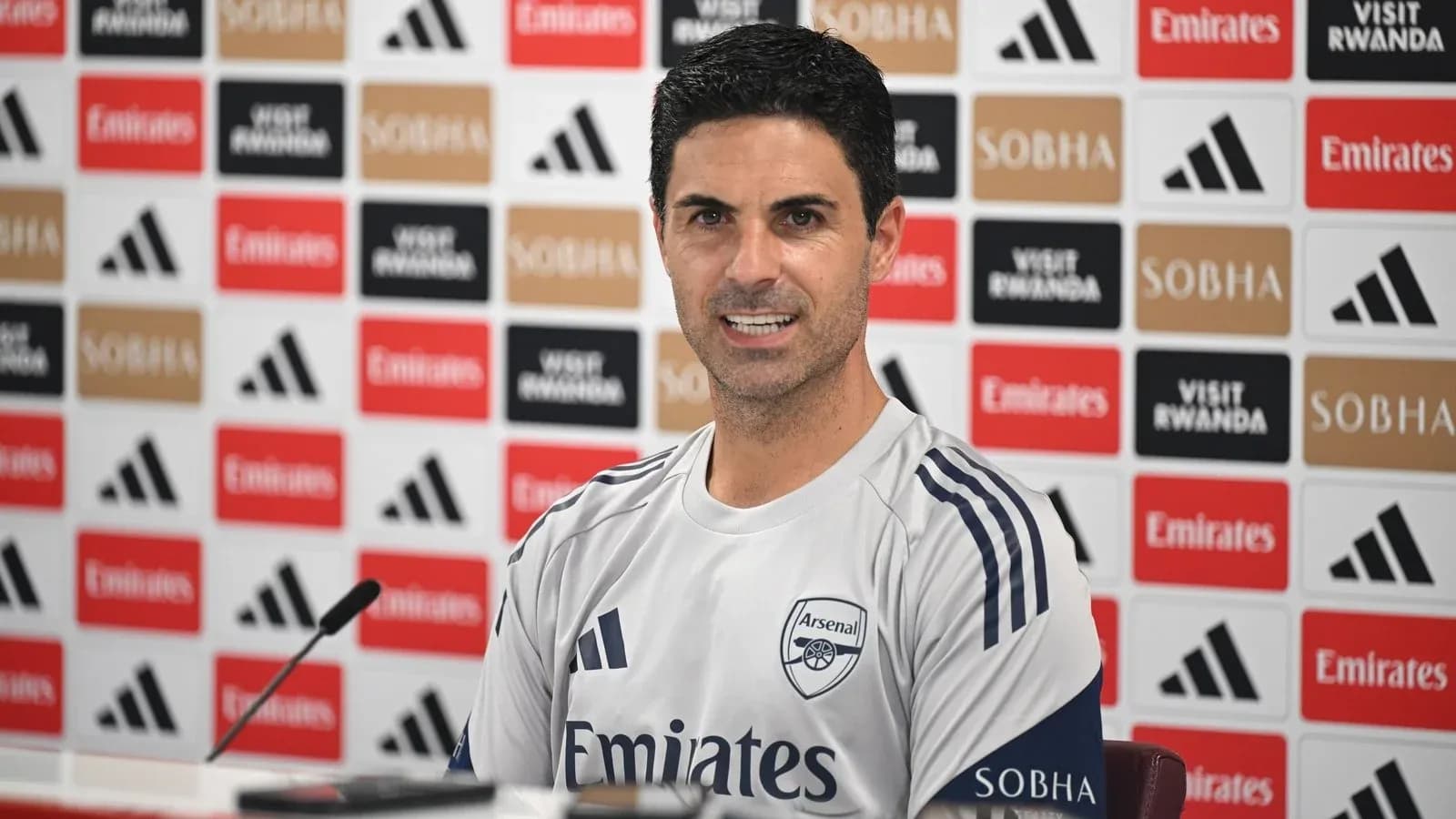 Manager speaking at press conference with Arsenal branding