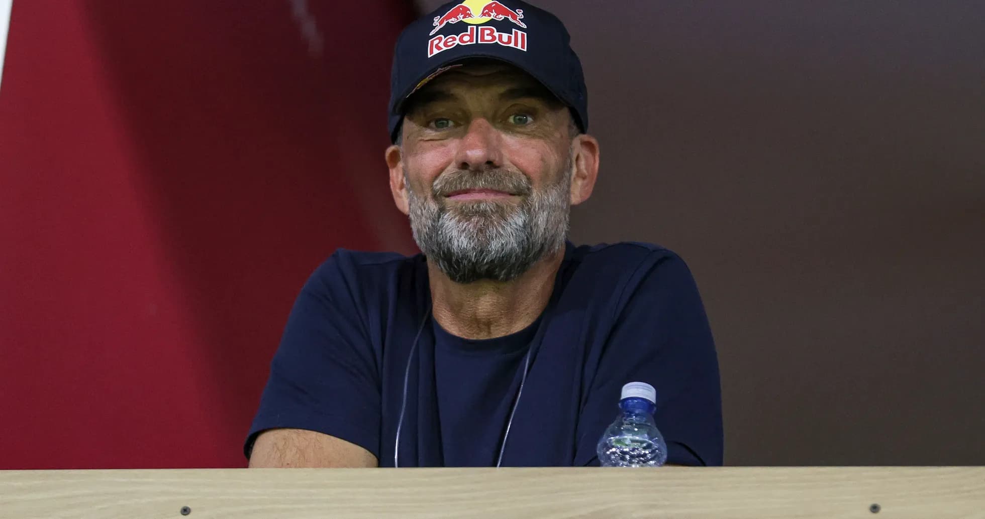 Man with beard wearing Red Bull cap in stands