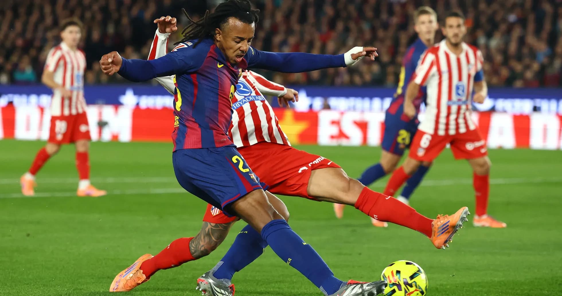 Barcelona player tackling Atletico Madrid opponent
