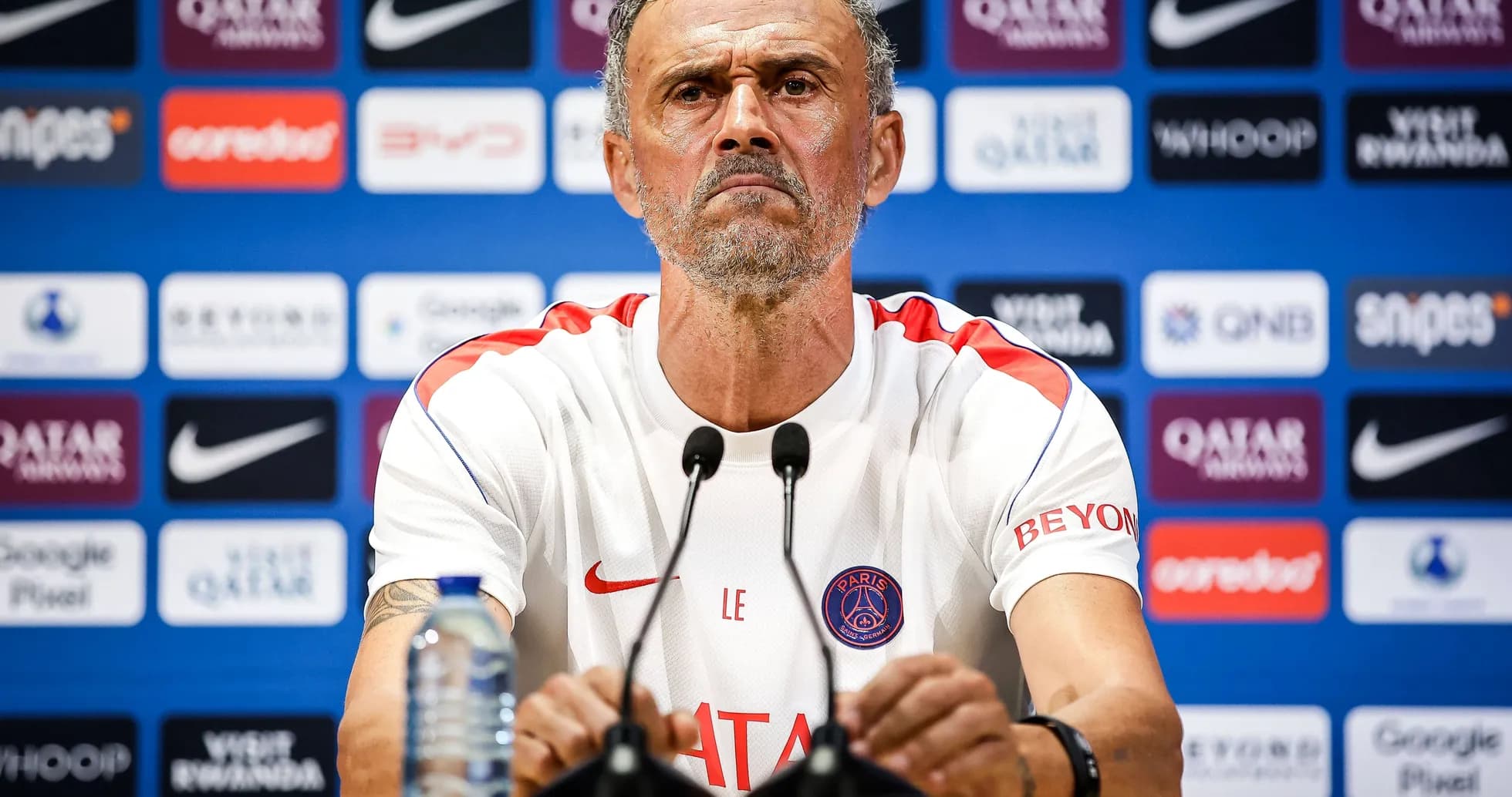 Manager speaking at press conference with team logo