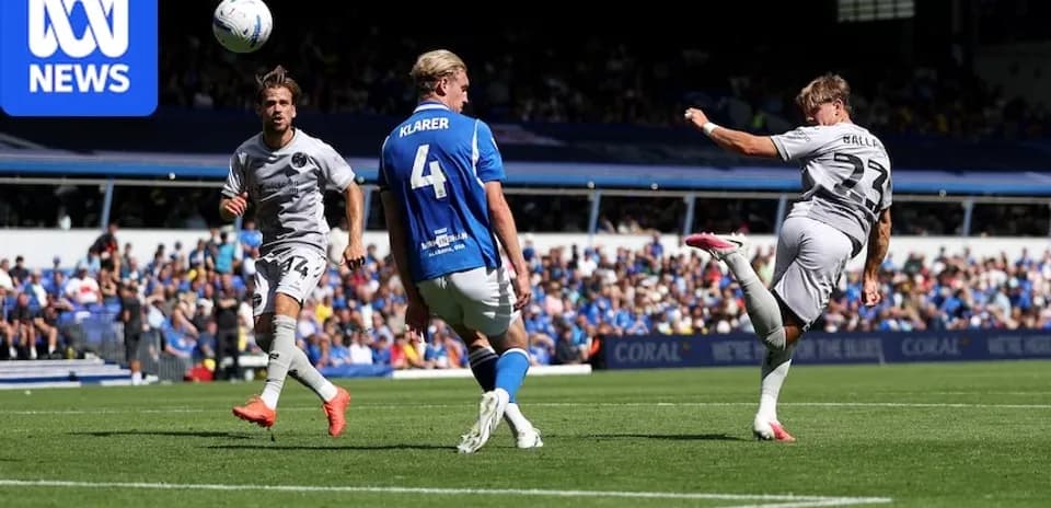 Player kicking ball during match with defenders nearby
