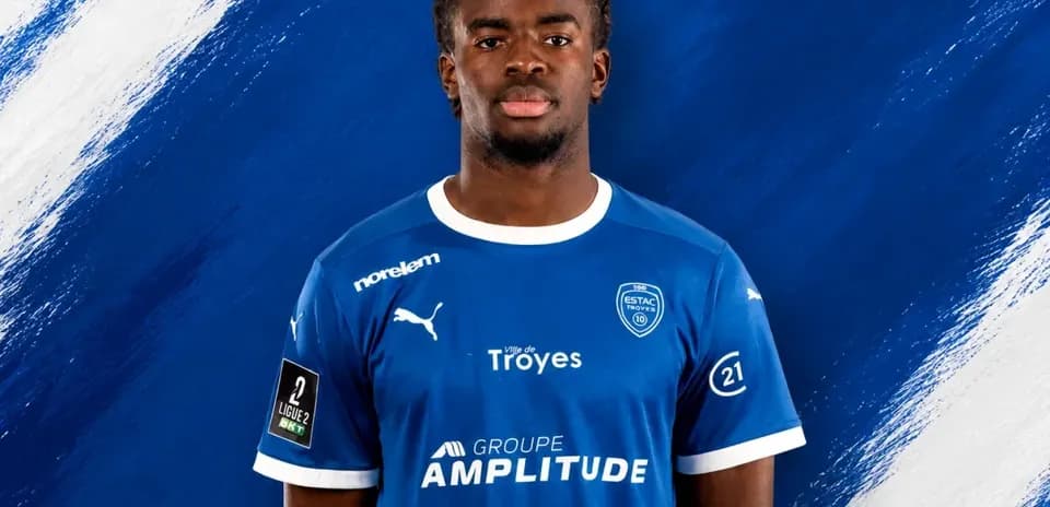 Player in blue ESTAC Troyes jersey on backdrop