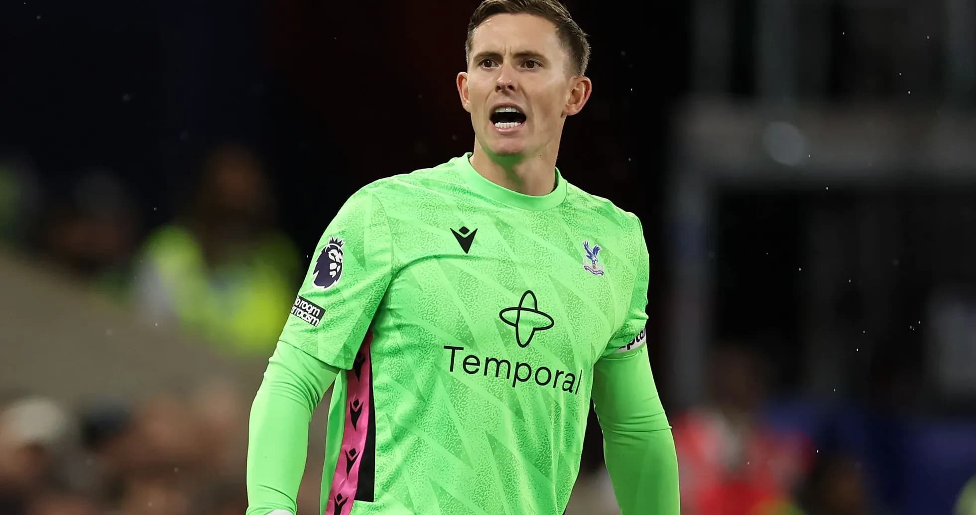 Goalkeeper in green kit directing play on field