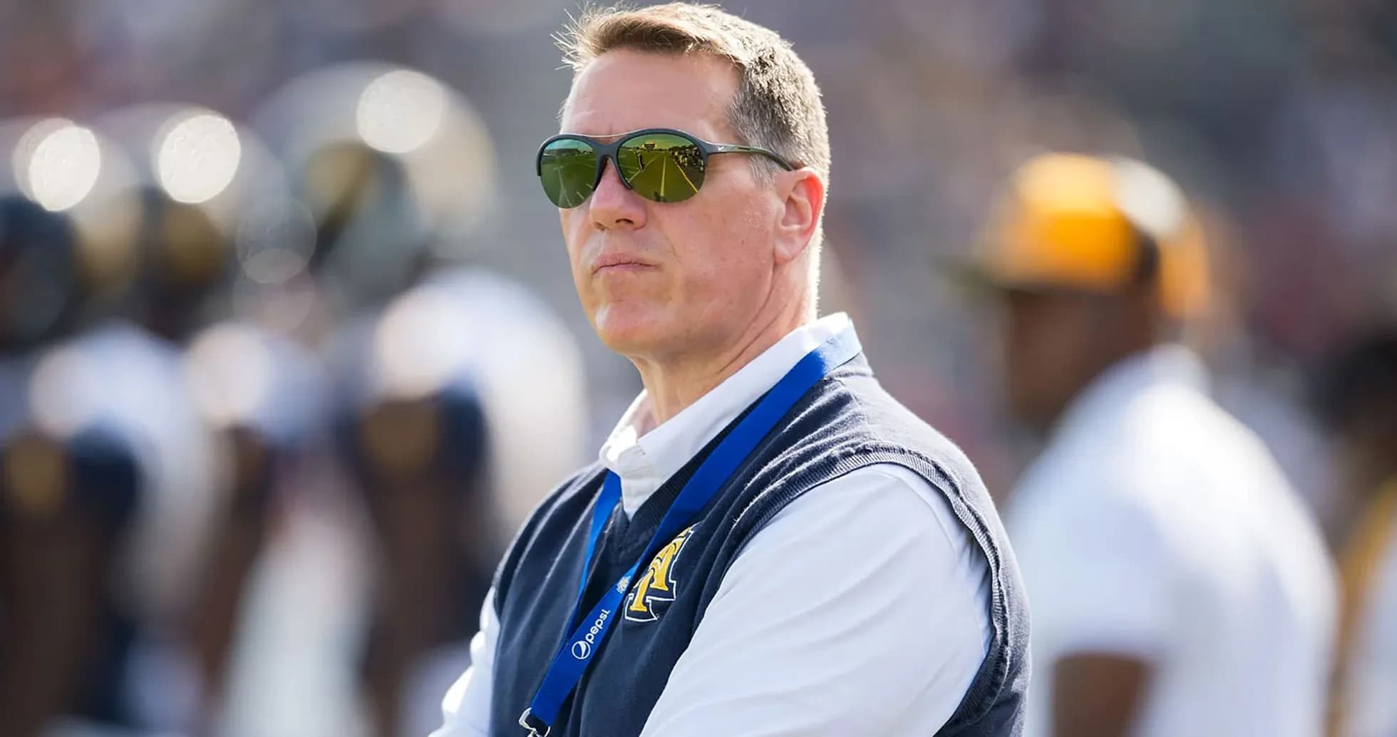 Man wearing sunglasses observing the football field