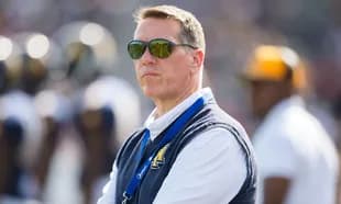 Man wearing sunglasses observing the football field