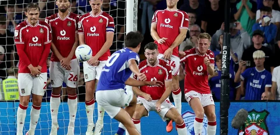 Player taking free kick while defenders form wall