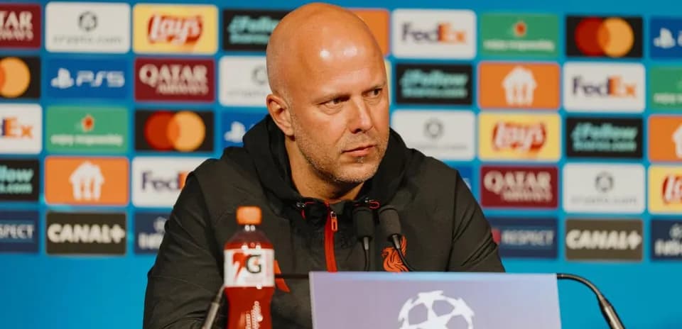 Manager at pre-match press conference with logos behind