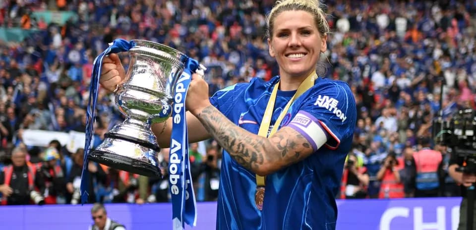 Player celebrating with trophy in stadium crowd