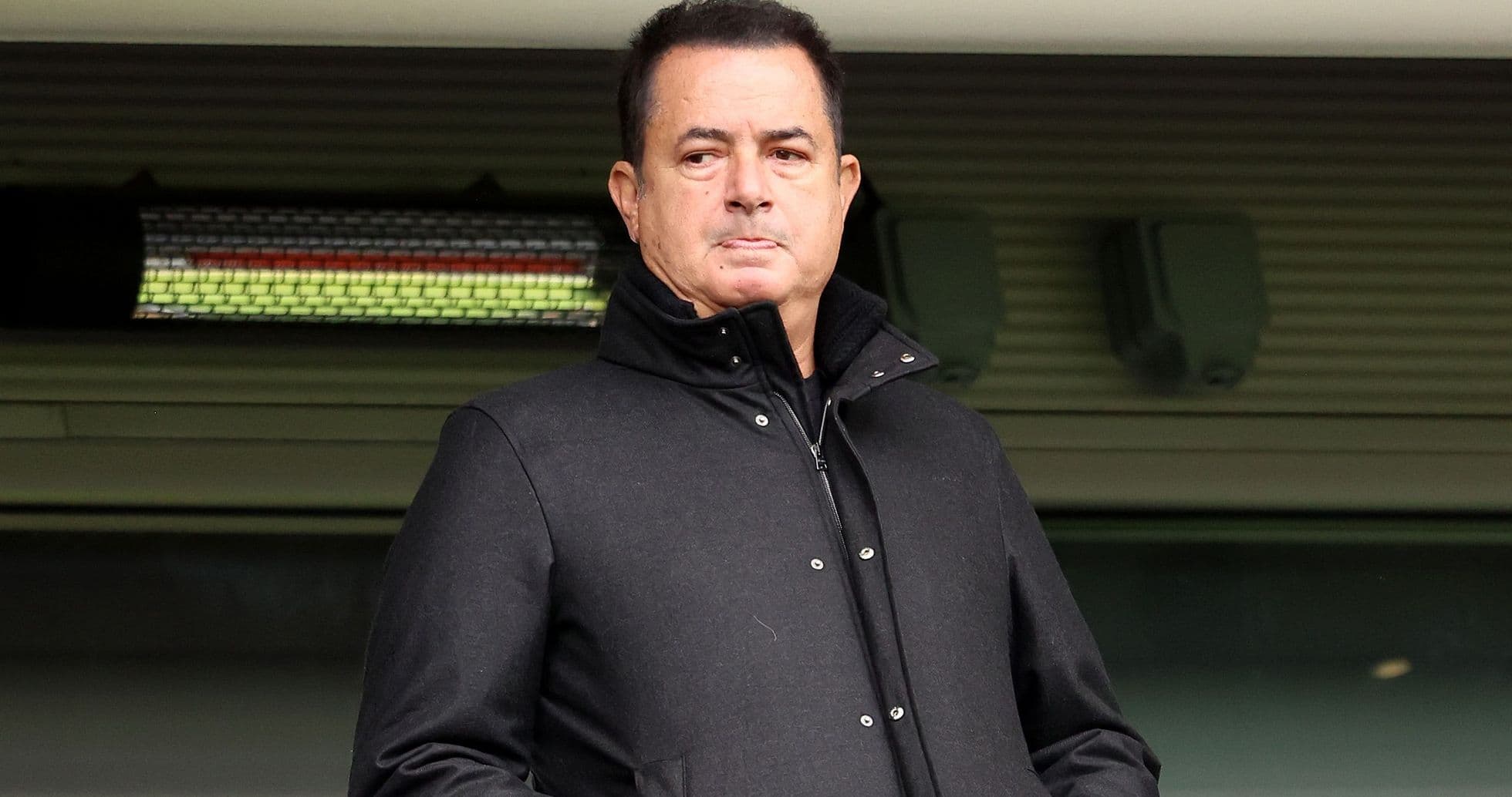 Man in black coat observing from the stands