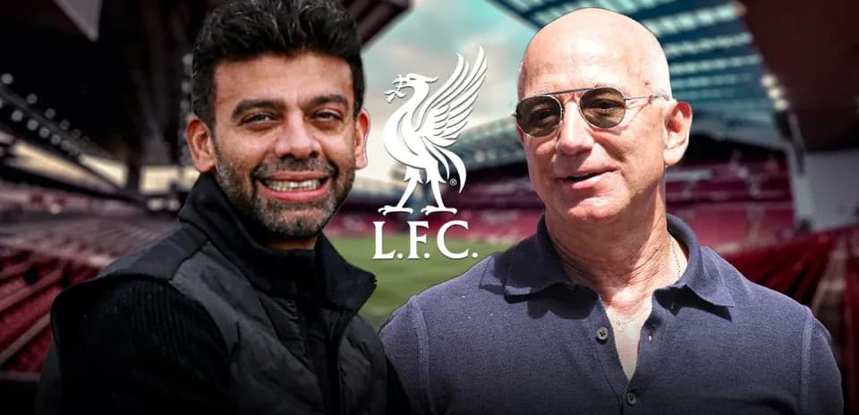 Two men smiling at Anfield stadium with L.F.C. logo