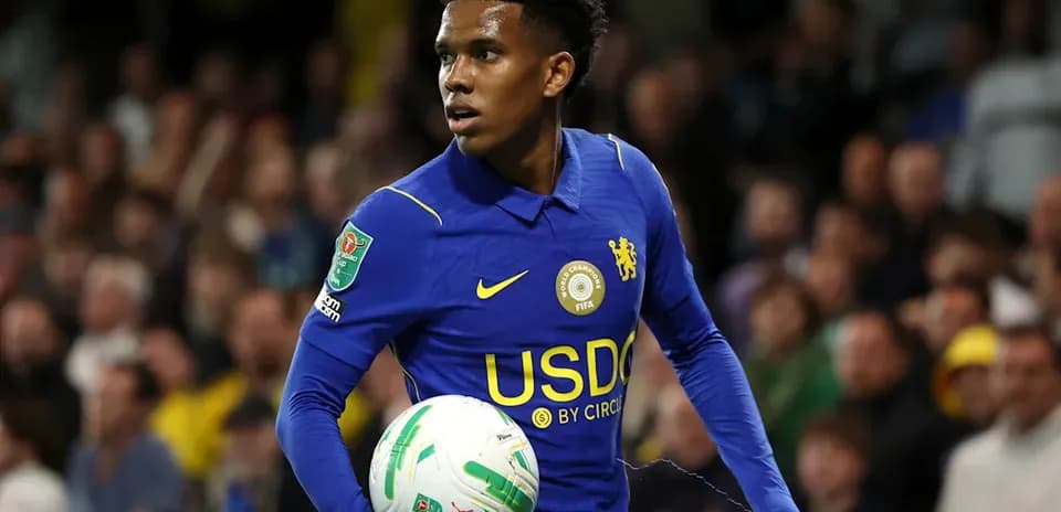 Player in blue jersey holding football on pitch