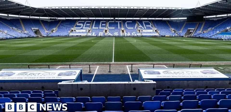 Empty football stadium with blue seating and pitch