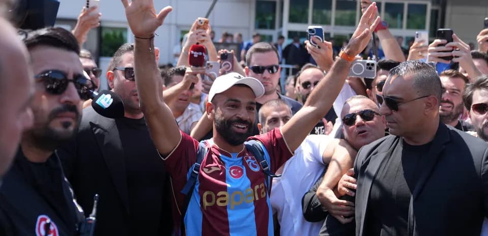 Player greeting fans surrounded by media and security
