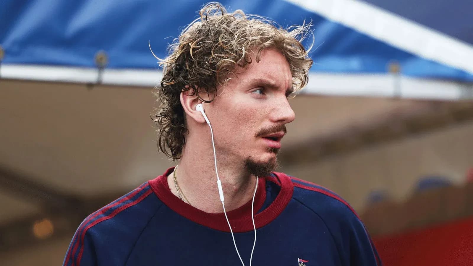 Athlete wearing earbuds, walking in casual attire