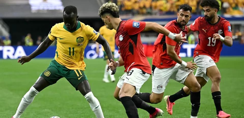 Australian player dribbling past Egyptian defenders during match