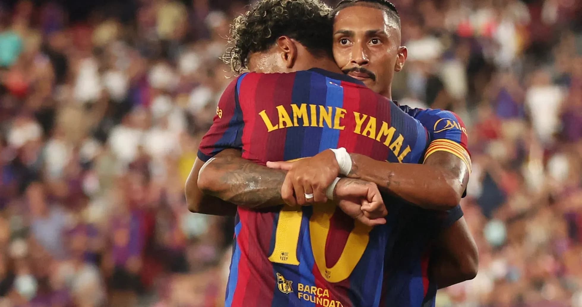 Two FC Barcelona players hugging on the field