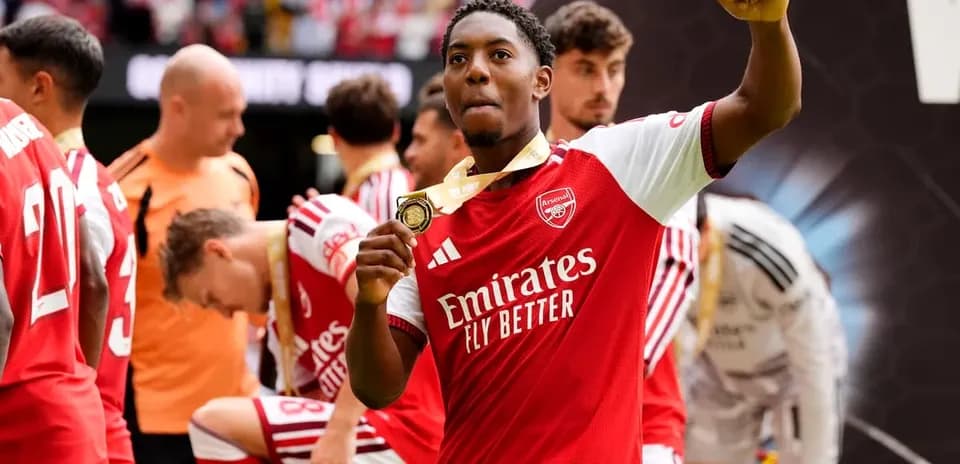 Arsenal player celebrating with a medal after match