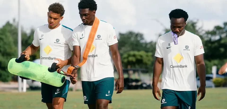 Three players carrying training equipment on field