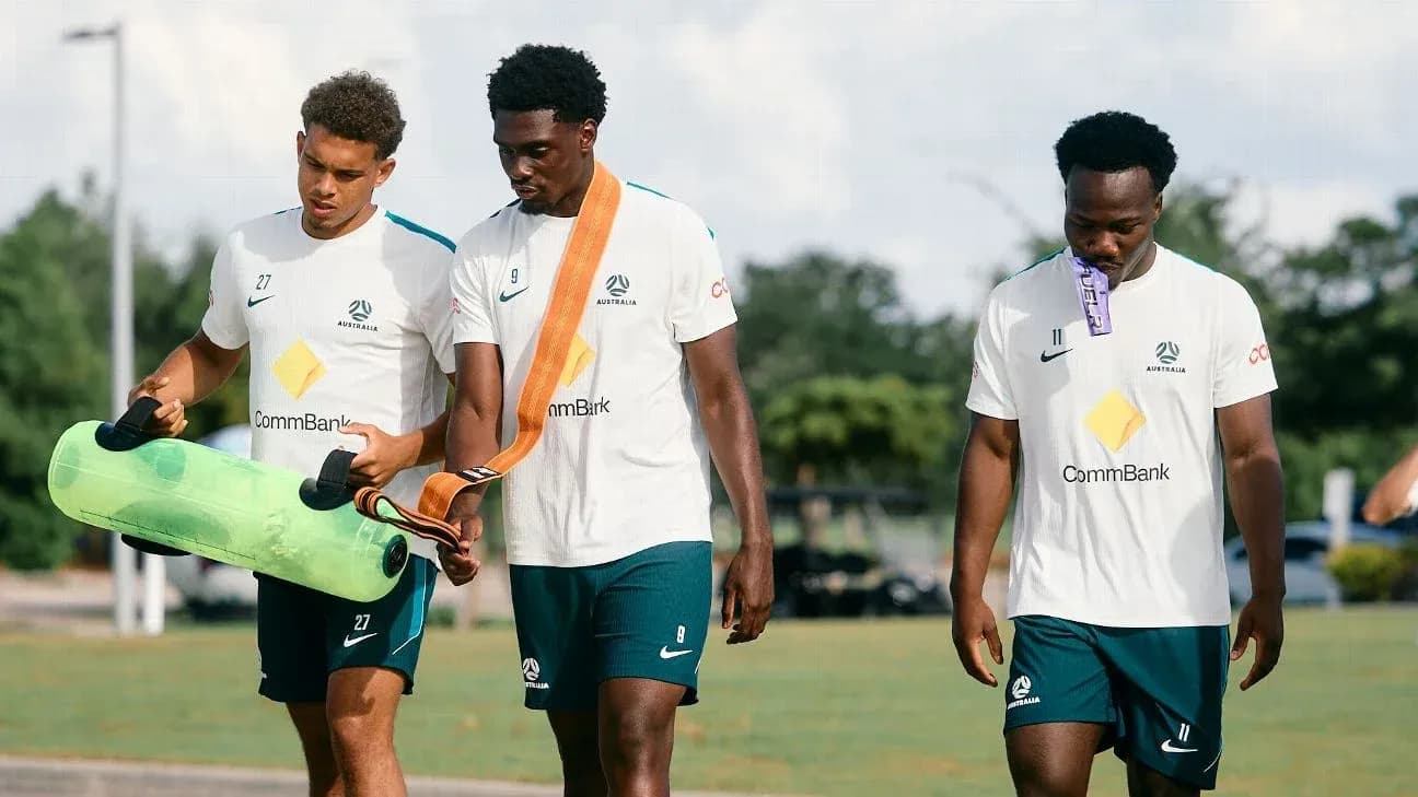 Three players carrying training equipment on field