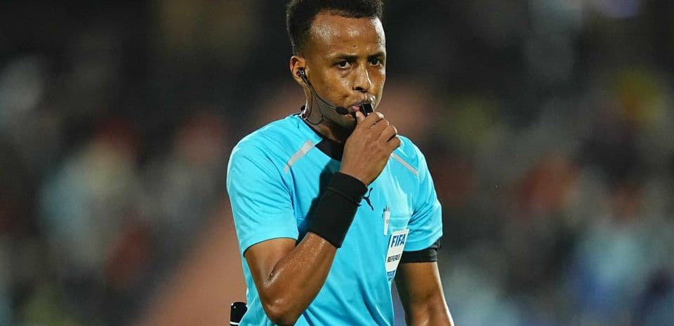 Referee blowing whistle during football match